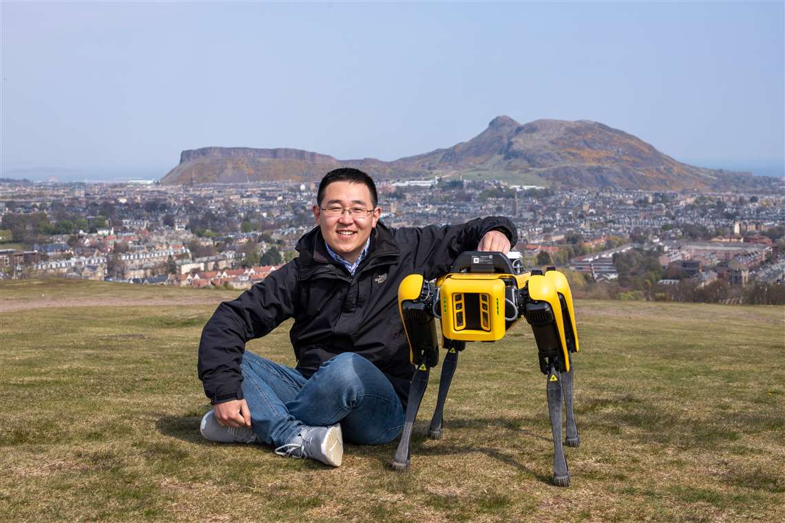 Dr Sen Wang with the new robot sitting down