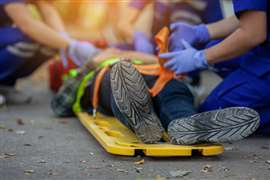 An injured worker lies on a stretcher, attended to by a team of paramedics