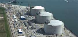 Aerial view of three LNG tanks under construction at a port.
