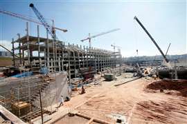 A construction site in Latin America, with cranes surrounding the concrete frame of a building.