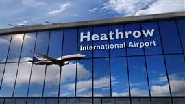 Image of a passenger jet reflected in the windows of a glass-fronted building bearing the words 'Heathrow International Airport'