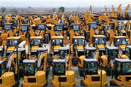 Rows of new yellow construction machinery in an industrial yard.