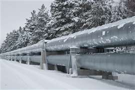 A pipeline in winter, covered in snow and set against a backdrop of snowy trees.