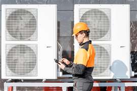 Workman servicing air conditioning or heat pump with digital tablet