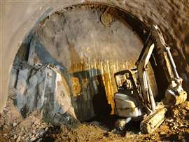 An excavator in front of a tunnel shaft.