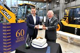 Anthony Bamford, in primo piano a destra, riceve il premio per i 60 anni di servizio dall'amministratore delegato della JCB Graeme Macdonald durante una presentazione a cui partecipano i direttori della JCB.