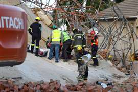 A rescue worker removes rubble from the site where construction workers are trapped under a building that collapsed in George, South Africa, 7 May 2024.