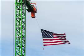 Uma bandeira americana tremulando pendurada em um guindaste de torre de construção