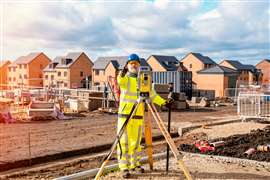 Surveyor builder site engineer with theodolite total station at construction site outdoors during surveying work