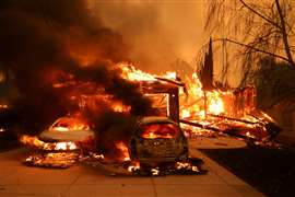 Des véhicules et une maison brûlent alors que des vents puissants alimentent des incendies de forêt dévastateurs dans la région de Los Angeles forcent les gens à évacuer, à l'incendie d'Eaton à Altadena, en Californie