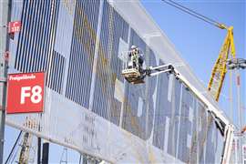 Trabalhadores fixam elementos decorativos na fachada externa do estande da Liebherr