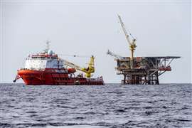 A construction support vessel moored next to a production satellite platform while performing an installation project
