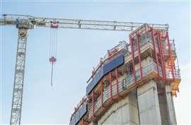 A construction site in Canary Wharf, London, with a large crane and a partially built concrete structure equipped with red scaffolding and safety barriers