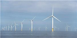 Wind turbines at sea, against a cloudy sky