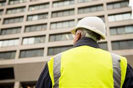 Construction worker / building inspector surveying a tall building