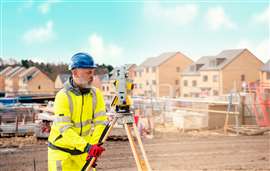 Surveyor builder site engineer with theodolite total station at construction site outdoors during surveying work