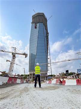 An employee of Schwing Stetter stands in front of La Tour F, a skyscraper in Abidjan, Côte d'Ivoire. La Tour F will be a government building in an administrative district called “Le Plateau”. It will be, by some measures, the tallest building in Africa after it was decided that a 70m antenna should be added to the 333m-tall building, making the entire structure 404m in height. The 74-storey building is based on a concrete structure up to 300m, with the levels above being built using steelwork. Belgian contractor Besix is responsible for all concrete works. Mobile truck-mounted concrete pumps were used for the lower segments and then from a height of 40m, a stationary high-performance concrete pumping system from Schwing Stetter was installed. At the heart of the system is the SP 7500D high-pressure pump, with a drive power of 310kW. All concrete work is set for completion this month. (Image courtesy of Schwing Stetter)