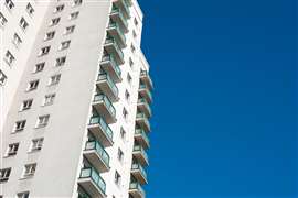 Low angle view of a high rise residential apartment block against a clear blue sky.