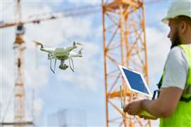 A construction worker or engineer uses a tablet and drone on a construction site. Image: Adobe Stock