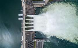 Aerial top down view of water discharge at hydroelectric power plant.