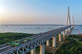 Il ponte Changtai sul fiume Yangtze in Cina, il ponte strallato con la campata più grande al mondo, è stato recentemente sottoposto a un test di carico critico sulla sua sezione combinata strada-rotaia prima dell'apertura al traffico. Primo ponte a due piani sul fiume Yangtze che integra una superstrada, una ferrovia interurbana e un'autostrada tradizionale, la struttura si estende per 10 chilometri di lunghezza, con una campata principale di 1.208 metri. La torre principale raggiunge i 352 metri. Adotta una struttura ibrida in acciaio e elementi compositi acciaio-calcestruzzo, secondo il China Railway Group, che lo ha costruito. La costruzione del ponte è iniziata nel 2019 e si prevede che sarà sostanzialmente completata nella seconda metà di quest'anno, con l'apertura della carreggiata per prima. (Immagine: China Railway Group)