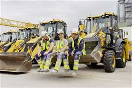 Three Porr apprentices sit in the bucket of a wheel loader