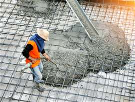 Top view of builders in orange shirt pouring concrete works on the construction site