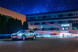 Um carro passa à noite em frente a um prédio da marca Onsemi.