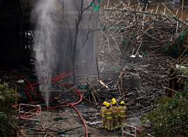 Los bomberos se reúnen junto a los restos de un andamio de bambú en el complejo de viviendas Wang Fuk Court después del incendio mortal, en Tai Po, Hong Kong, China. (Imagen: Reuters/Maxim Shemetov)