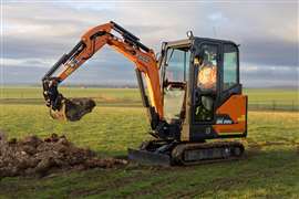 Yellow mini excavator digging in a field