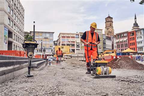 Construction site worker using a vibratory plate to compact soil