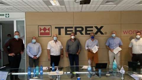 Lineup of people in masks below Terex logo in office