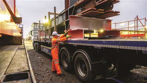 Construction worker lifting prefab materials