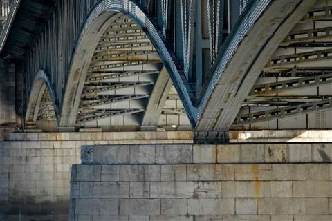 The arches of a metal bridge as viewed from below.