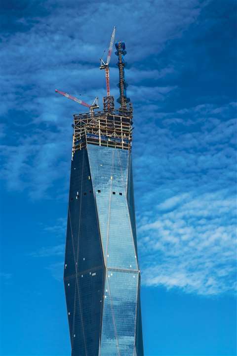 Merdeka 118 in Kuala Lumpur, Malaysia set against a blue sky with two red and white tower cranes visible at the top.