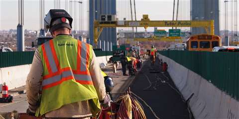 A Tutor Perini worker in branded workwear with his back to the camera on a construction site