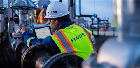 A Fluor worker in yellow hi-vis and white hard hat