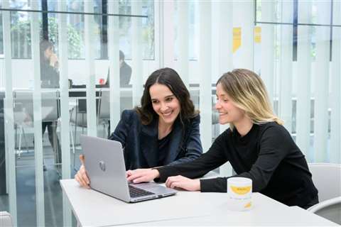 Two smiling Ferrovial employees try out the new AI assistant on a laptop
