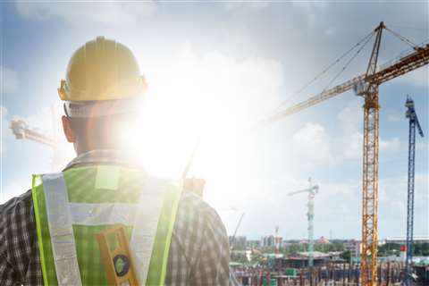 A construction worker's back as they look towards a site in blazing sunshine, highlighting the risk of skin cancer..