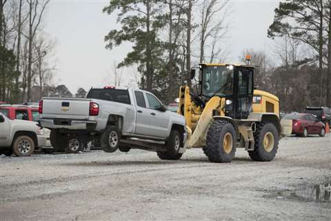 Cat 938M small wheeled loader with forks lifting a pick-up truck